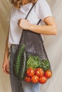 Girl holding mesh shopping bag with vegetables. Sustainable, zero waste and plastic free