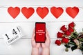 Girl holding mobile phone with sign Happy Valentines Day in hands, garland of red paper hearts, bouquet of roses Royalty Free Stock Photo