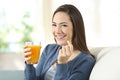 Girl holding an orange juice and a pill looking at you Royalty Free Stock Photo