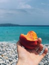 the girl is holding a peach on the background of the blue sky Royalty Free Stock Photo