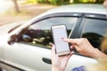 Girl holding a phone in the background of the car. Theme car rental using phone car sharing