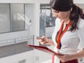 The girl is holding the phone in her hands. Beautiful Smiling Businesswoman Standing Against White Offices Background. Portrait of Royalty Free Stock Photo