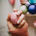 The girl is holding a pink easter egg on a stand, pink and marble background, minimalism