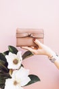 Girl holding a pink wallet on a gentle pastel background with a flower.