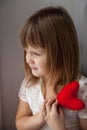 Girl holding a red knit heart and waits for Valentine's Day Conc