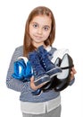 The girl is holding several pairs of shoes.