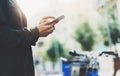 Girl holding smart phone on background sun atmospheric city and bike, hipster using in female hands and texting mobile, street Royalty Free Stock Photo