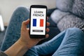 Girl holding smart phone with learn French concept on screen Royalty Free Stock Photo