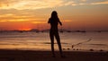 Girl holding smart phone and taking red sunset photo on the tropical beach.  Silhouette of a woman, yachts and mountains on Royalty Free Stock Photo