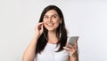 Girl Holding Smartphone Enjoying Song In Earphones, White Background Royalty Free Stock Photo