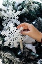 A girl holding a snowflake on the christmas tree.