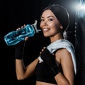 Girl holding sport bottle and smiling isolated on black