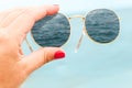 girl holding sunglasses in her hands on a background of blue sky in glasses displays the sea.