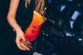 Girl holding Sweet Famous juicy red with orange Author inspired Cocktail Drink -on bar counter . Female Close-up Top view . Copy