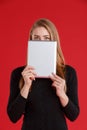 A girl holding a tablet in her hands and covering her face with them. Royalty Free Stock Photo