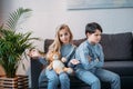 Girl holding teddy bear while offended boy sitting on sofa at home Royalty Free Stock Photo