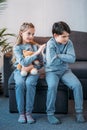 Girl holding teddy bear while offended boy sitting on sofa at home Royalty Free Stock Photo