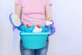 The girl is holding a turquoise plastic basin with cleaning supplies for cleaning