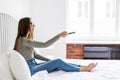 Girl holding a TV remote, changing the channel. Young woman sitting at home with the remote control watching television alone. Royalty Free Stock Photo