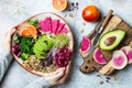 Girl holding vegan, detox Buddha bowl with quinoa, micro greens, avocado, blood orange, broccoli, watermelon radish