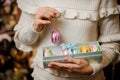 Girl holding a violet macaroon and box of many glittering toy bulbs of different colors Royalty Free Stock Photo