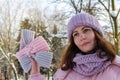 Girl holding warm knitted women& x27;s headbands of pink and purple colors
