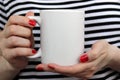 Girl is holding white cup in hands.