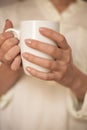 Girl is holding white cup in hands. White mug for woman, gift. Female hands holding hot cup of coffee or tea in morning Royalty Free Stock Photo