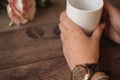 Girl is holding white cup in hands. White mug for woman, gift. Female hands with watch and bracelets holding hot cup of coffee Royalty Free Stock Photo