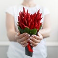 Girl holds by both hands a small bouquet made of red hot pepper in the shape of a heart