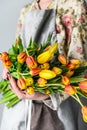 A girl holds a bouquet of yellow, orange and red Tulips. White background