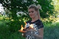 Girl holds a burning book in her hands. A young woman in a forest burns a book Royalty Free Stock Photo