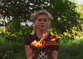 Girl holds a burning book in her hands. A young woman in a forest burns a book