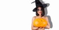 A girl holds a carved Jack-o ` - Lantern pumpkin. Funny woman in a witch hat and makeup for Halloween Royalty Free Stock Photo