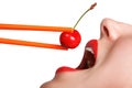 Girl holds chopsticks a red sweet cherry near lips Royalty Free Stock Photo