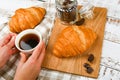 Girl holds a coffee mug. on the background of a croissant. coffee with a croissant. the beginning of the morning. Coffee cup. Top