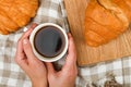 Girl holds a coffee mug. on the background of a croissant. coffee with a croissant. the beginning of the morning. Coffee cup. Top