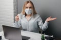 Girl in the office sits in a mask and tries to drink coffee but nothing works out