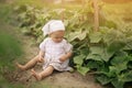 Dirty unwashed fruit. Hungry child is sitting on the earth in a vegetable garden