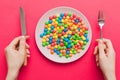 the girl holds cutlery in her hands and eats sweets in a plate. Health and obesity concept, top view on colored