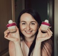 The girl holds delicious cupcakes with white cream in her hands, decorated balls with coconut powder. Holds cupcakes close to her Royalty Free Stock Photo