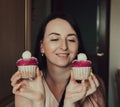 The girl holds delicious cupcakes with white cream in her hands, decorated balls with coconut powder Royalty Free Stock Photo