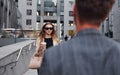 Girl holds drink. Woman and man in the town at daytime. Well dressed people