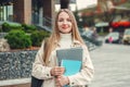 girl holds folders notebooks books in hands smiles look at camera against the background of a modern university building Royalty Free Stock Photo