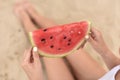 Girl holds red watermelon slice in hands. picnic on the beach. young woman sit on sand in summer vacation. shallow depth of field Royalty Free Stock Photo