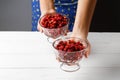A girl holds a glass bowl with ripe red strawberries. Close up. Free space. Copy spase