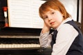 Girl holds her face with hand on the piano