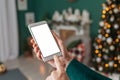 Girl holds her finger in front of smartphone mockup screen. against the background of New Year`s and Christmas cozy interior Royalty Free Stock Photo