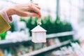 The girl holds in her hand a decorative house with decorations on the Christmas tree. Against the background of the counters of