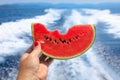 A girl holds in her hand a slice of bitten watermelon on the background of the sea. Taste of summer sea holidays concept